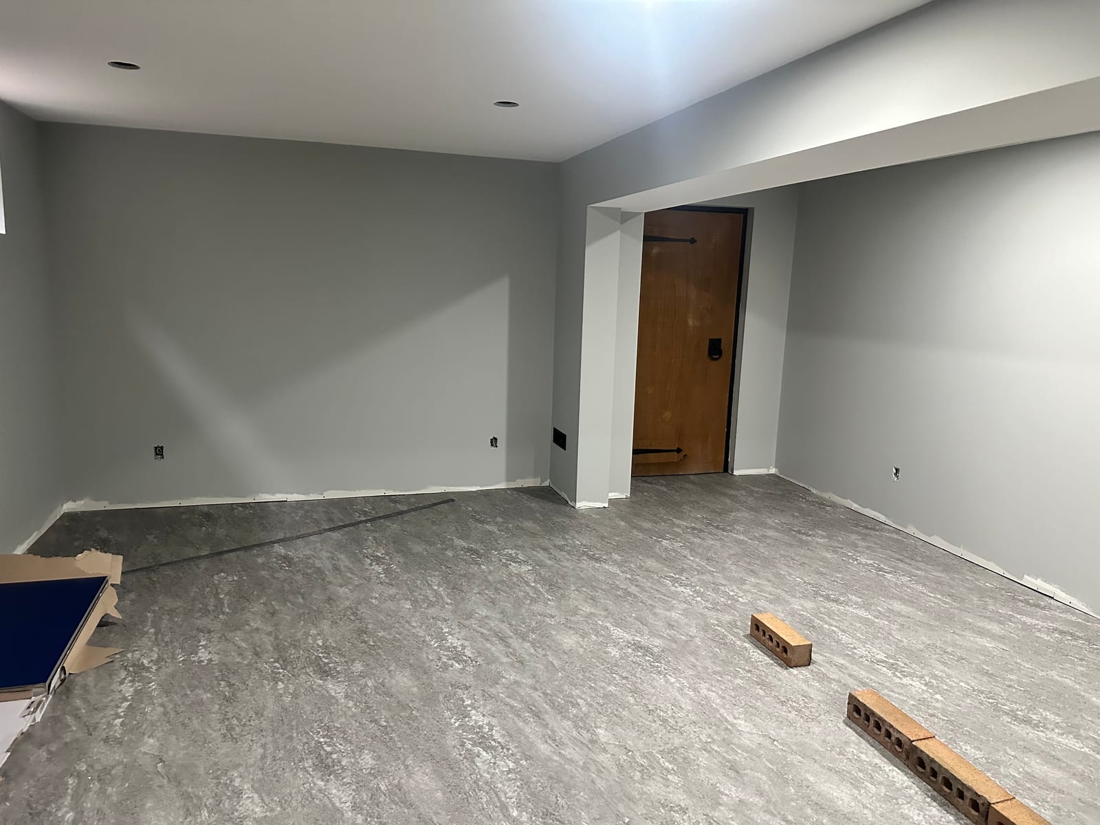 Basement room with finished grey walls, bulkhead, and flooring